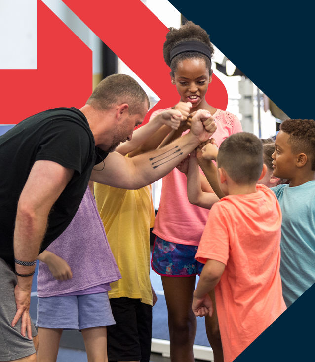 ACE Youth Fitness Specialist leading a group of kids in a fitness setting, all reaching in for a group fist bump